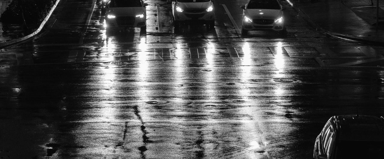 Headlights reflected on a rain-soaked intersection in downtown Miami at night