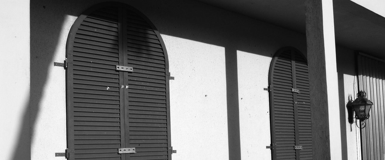 Closed hurricane shutters on the arched windows of a Florida house